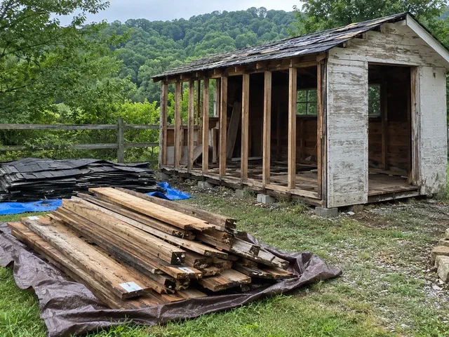 Weathered backyard shed partly taken apart with its lumber stacked on a tarp